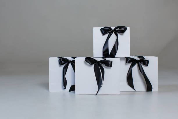 istock Four white paper gift bags with black bows on a gray background 1458444625