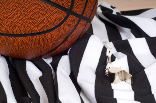 A basketball referee items including a basketball, a uniform and whistle.  Authority or sport's background etc.