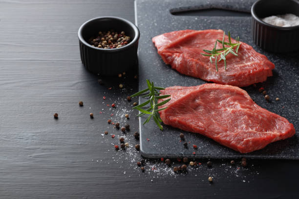 istock Raw beef steak with spices on a dark cutting board. Copy space. 1458449076