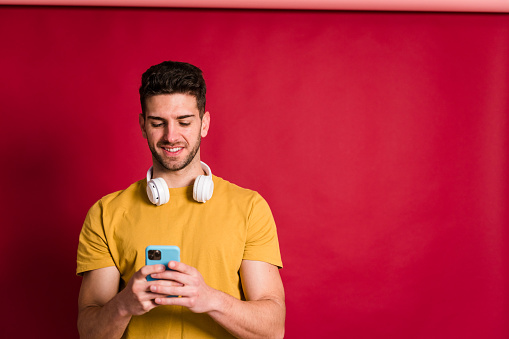 Studio shot of a young man holding smart phone and headphones