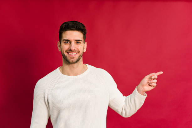 istock Cheerful young man pointing to the left on red background 1458450553