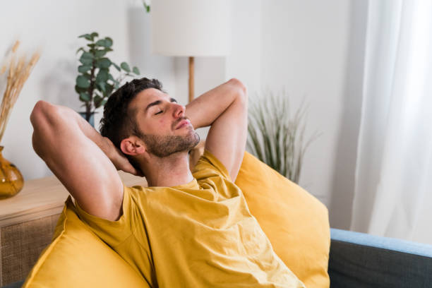 istock man stretching arms on sofa in living room 1458450647