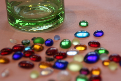 Colorful glass stones in front of a large glass bottle