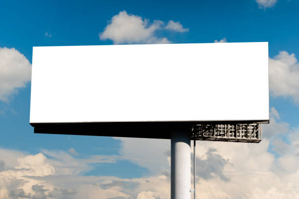 istock Blank wide white billboard against blue sky with white clouds - mock up 1458458420