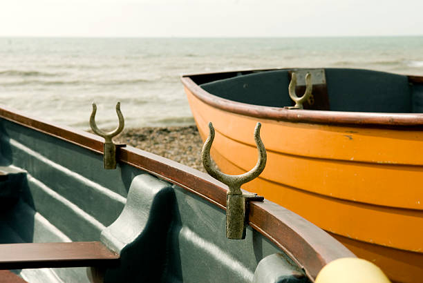A serene lakeside scene featuring a teal boat beached on a grassy shore, with a small wooden dock in the distance under a bright blue sky.