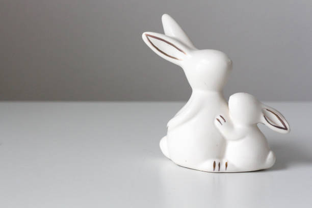 istock Two small ceramic bunnies on a white table and a white background. Festive home decor. Easter concept. 1458463470