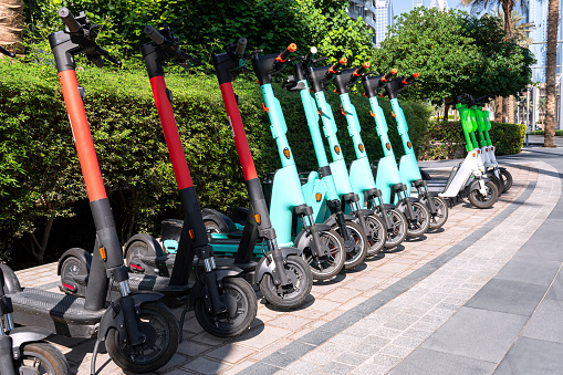 lots of electric scooters scooters in row on parking lot. City bike rental system, public kick scooters on the street