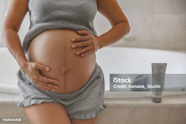Unrecognizable Pregnant Indonesian Woman Applying A Stretch Mark Cream Stock Photo - Download Image Now