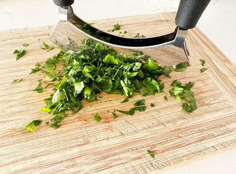 chopping parsley with mandolin on wooden cutting board