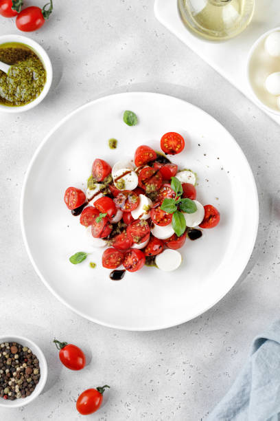 istock Caprese Salad with ripe tomatoes, mozzarella cheese, fresh basil, balsamic sauce, pesto on white plate. Healthy delicious diet salad. 1458476199