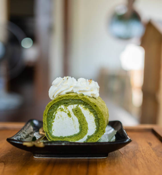 Cake (bread) matcha green tea roll placed on a black ceramic plate. stock photo