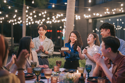 Asian Chinese friends celebrating birthday outdoor dining at night