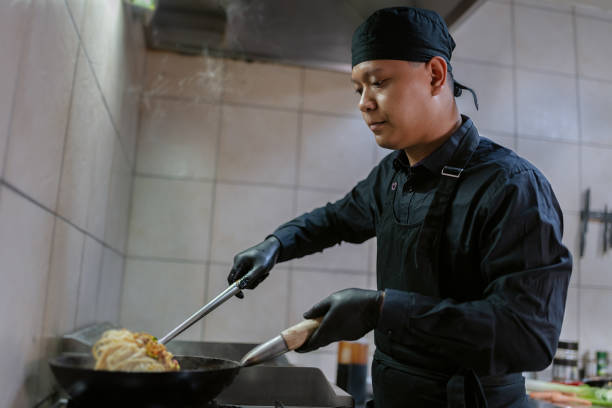 istock A chef in a black uniform prepares a meal. 1458481757