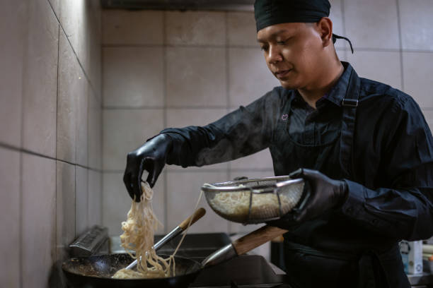 istock A chef in a black uniform prepares a meal. 1458481783