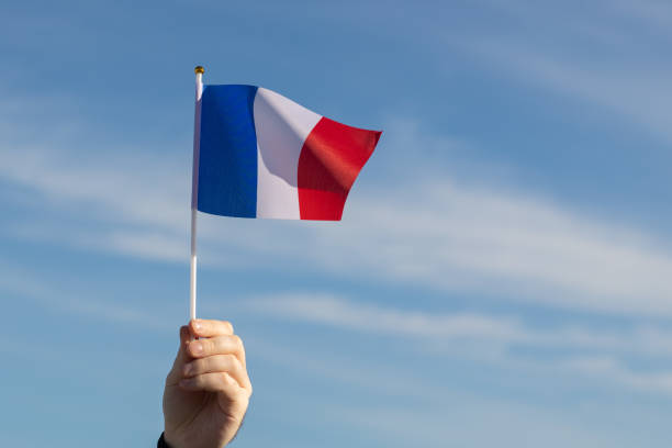 istock french flag in hand flutters in the wind against the sky 1458482418