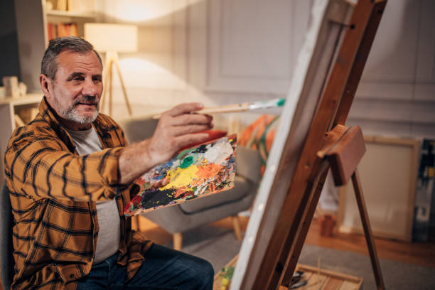 istock Senior artist paints on a canvas in his studio 1458483811