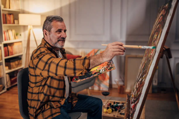 istock Senior artist paints on a canvas in his studio 1458483814