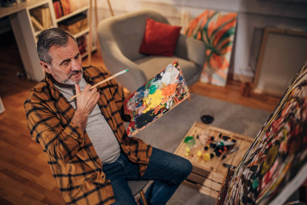 istock Senior artist paints on a canvas in his studio 1458483849