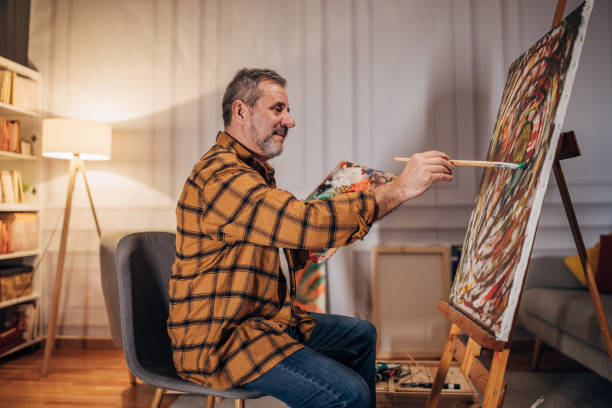istock Senior artist paints on a canvas in his studio 1458483873