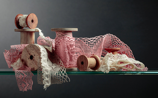 Vintage pink and beige cotton lace trims on wooden spools.