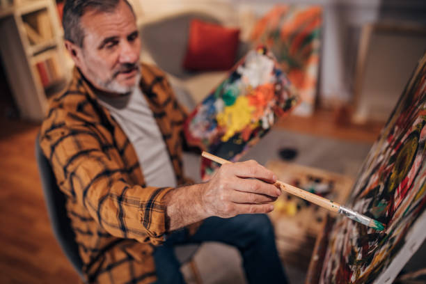 istock Senior artist paints on a canvas in his studio 1458483932