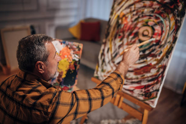 A male artist paints on a canvas in his studio