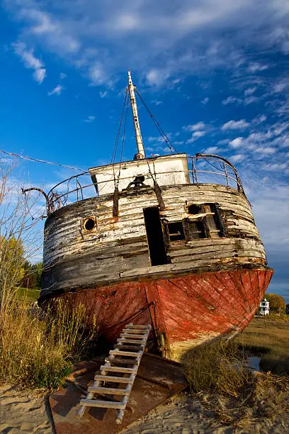 Photo of an abandoned shpireck left ashore, with dark blue sky