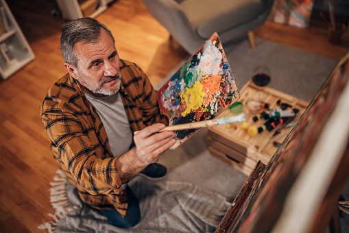 A male artist paints on a canvas in his studio