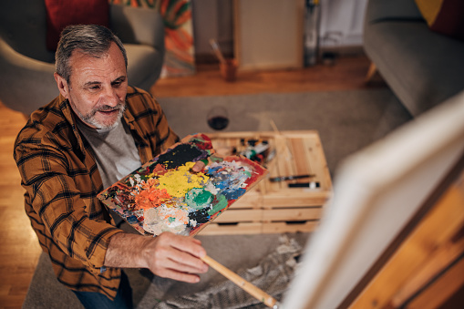 A male artist paints on a canvas in his studio