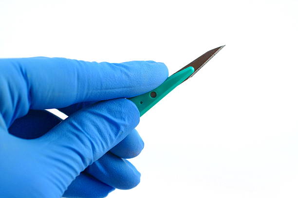 gloved hand holding scalpel stock photo