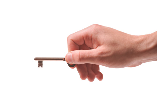 Person holding a door key isolated on white