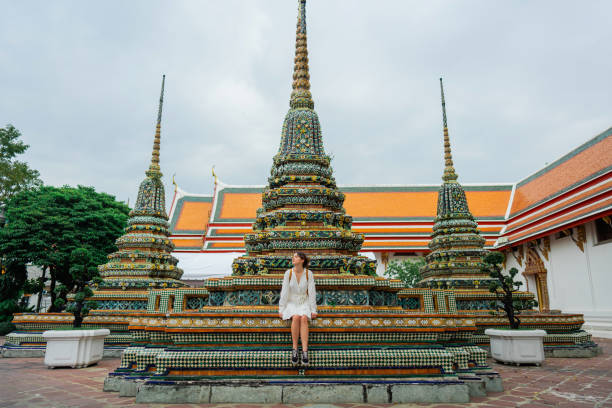 femme assise près de la pagode dans le temple wat pho à bangkok - wat pho photos et images de collection