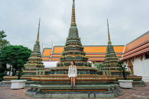 donna che si siede vicino alla pagoda nel tempio di wat pho a bangkok - wat pho foto e immagini stock