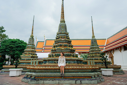 Woman sitting near pagoda in   Wat Pho temple in Bangkok