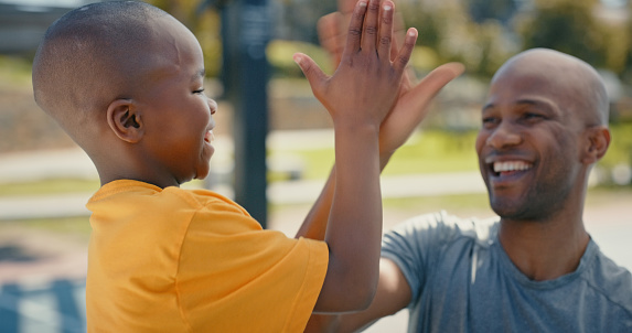 High five, black man and boy with winning team and support with happy family outdoor, solidarity and trust. Father, son and quality time together, motivation and partnership with success and winner