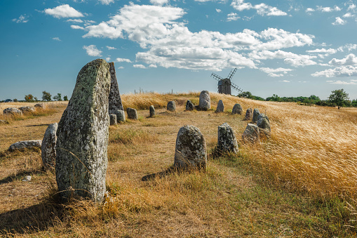 Ancient cemetery on Öland (Sweden) with rune stones. Possibly dates to about 1000 BC. Photo was made in the Norra Möckleby region. In the background one of the wooden mills that is characteristic for this island.