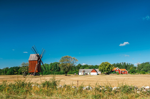 Characteristic landscape on the island of Öland (Sweden) with wooden mill and a farmhouse painted red and white