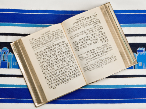 A Jewish prayer book, or Siddur, open and on top of a Jewish prayer shawl or Tallit.