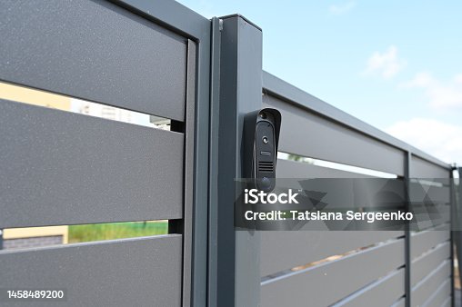 istock Black intercom call panel on a mounted in panel fence in anthracite color, visible wicket.Entrance to the private house. 1458489200