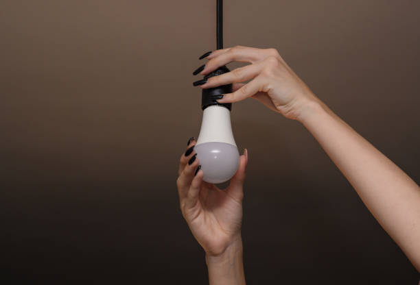 istock led lamp. Women's hands screw in a light bulb. 1458491853
