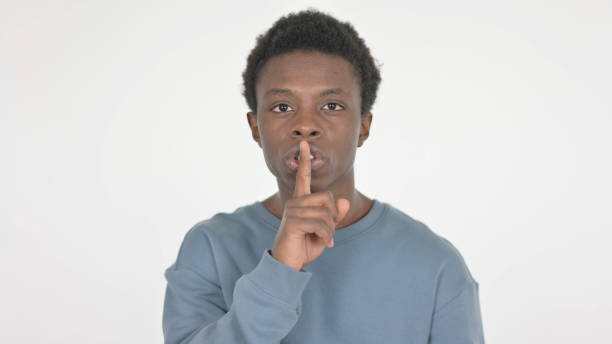 istock Young African Man with Finger on Lips, Silence on White Background 1458492335