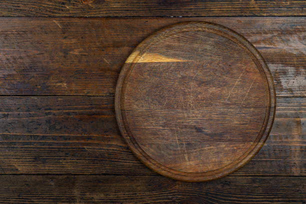 istock Cutting kitchen board on brown wooden table. Space for text. 1458492394