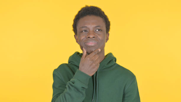 istock Brainstorming Young African Man Thinking Idea on Yellow Background 1458492737