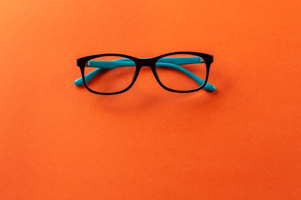 istock Stylish eyeglasses over orange background. Optical store, glasses selection, eye test, vision examination at optician, fashion accessories concept. 1458492814