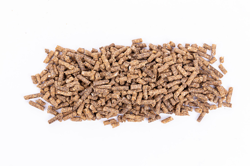 Sunflower granulated feed  on white background, close-up. Pile of sunflower meal pellets on white background. Heap of animal feed pellets  on white background.