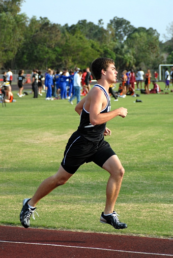 Below view of two determined male athletes running a relay race.