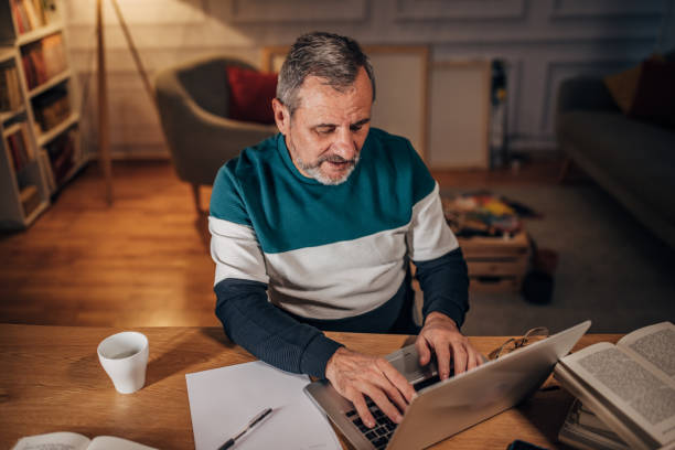 istock Male writer with beard uses laptop, working late 1458494343