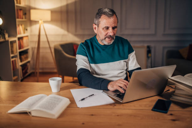 istock Male writer with beard uses laptop, working late 1458494363