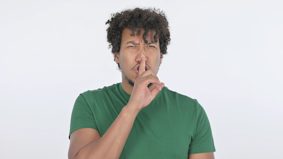 Casual African Man with Finger on Lips, Silence on White Background