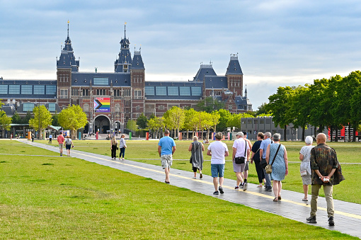 Amsterdam, Netherlands - August 2022: People walking through a park towards the famous Rijks Museum in the city centre